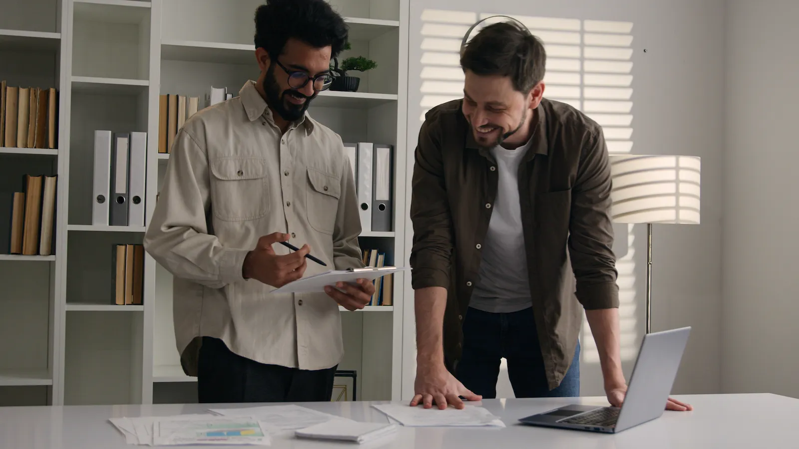 A consultant and a firm principal reviewing a printed workflow diagram beside a screen showing a folder structure