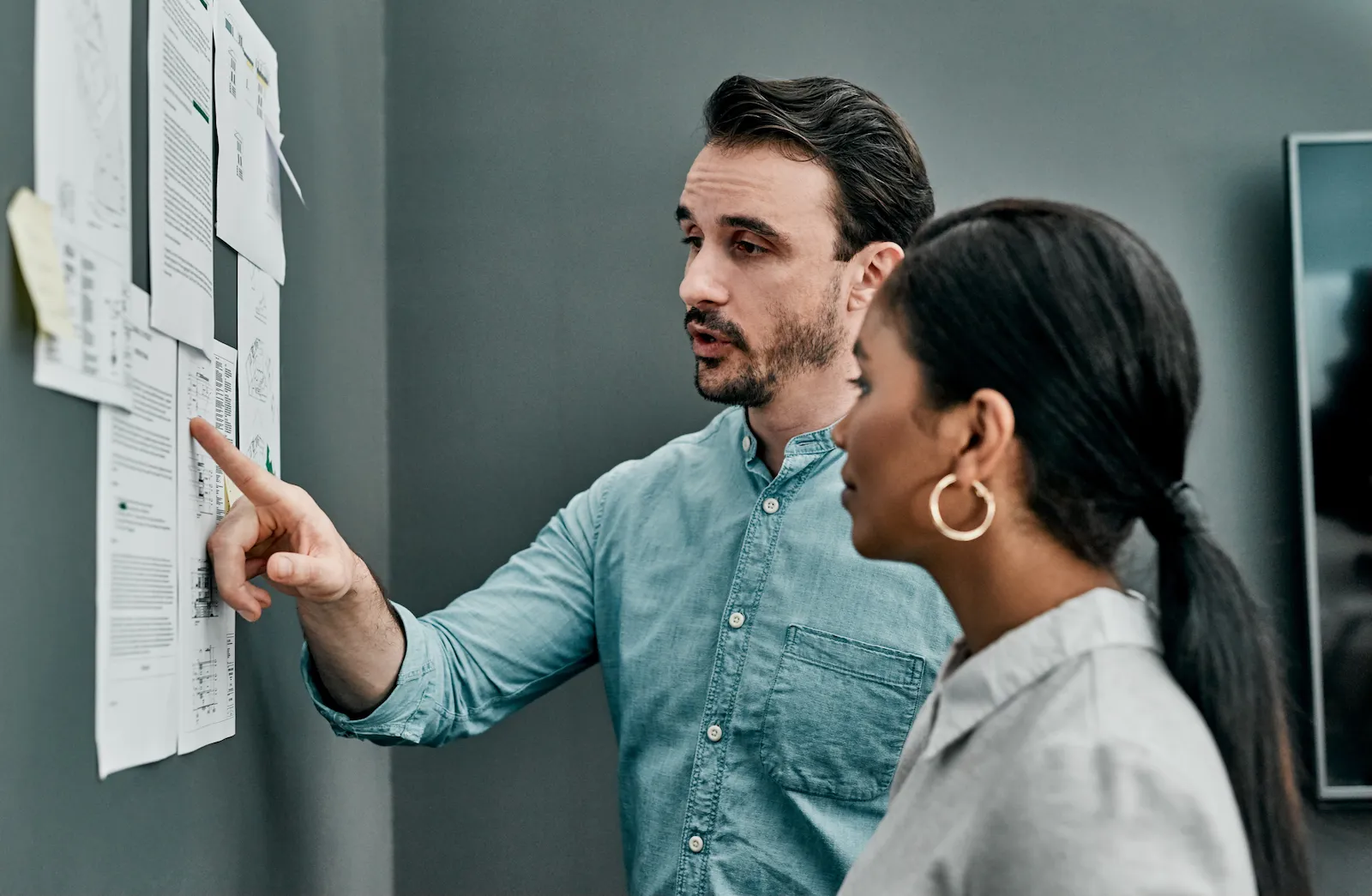 Two modellers comparing an architectural drawing sheet against the 3D model on screen